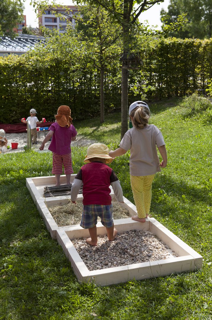 Kinder spielen im Garten, von hinten gesehen